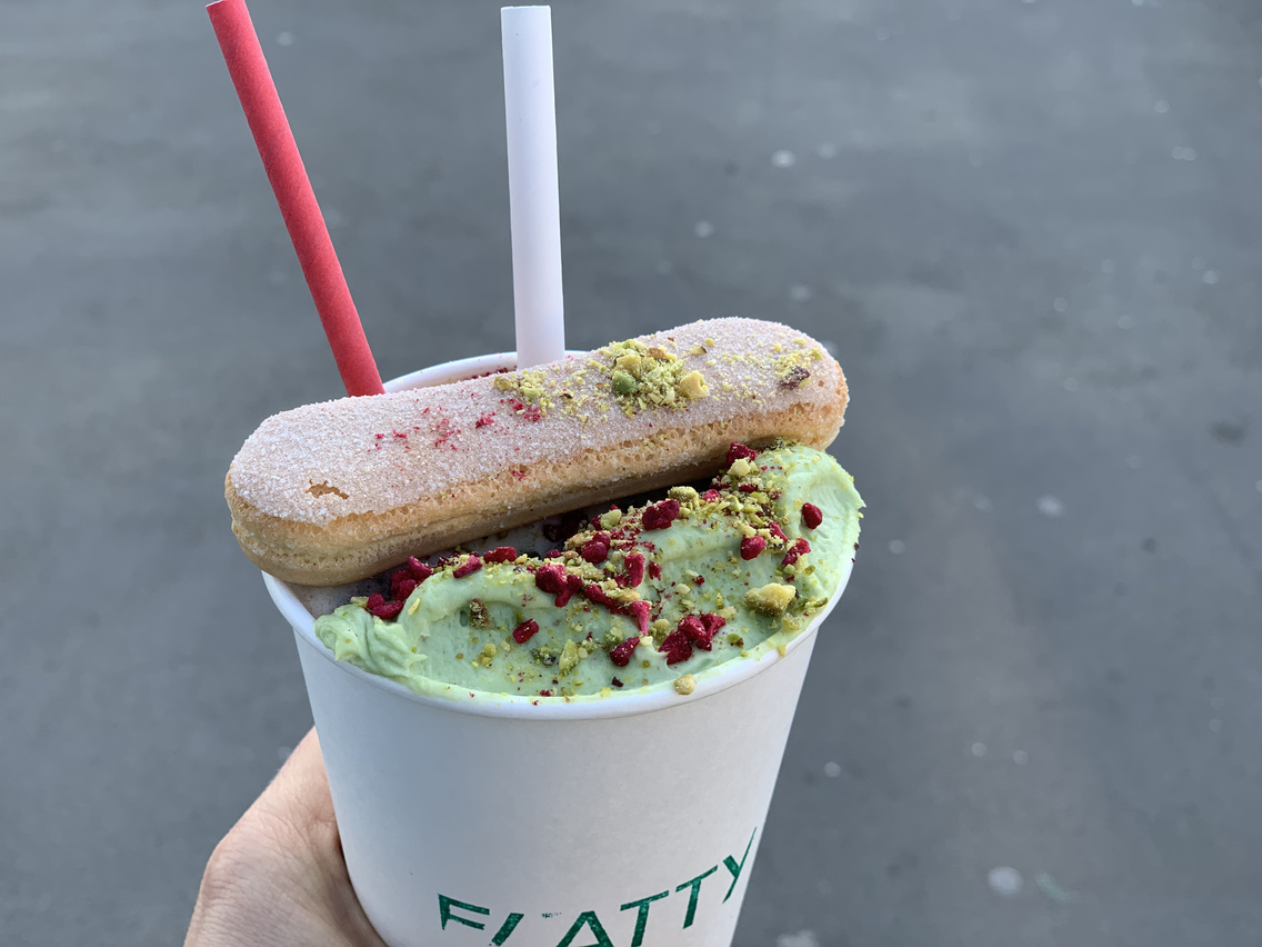 Matchamisu latte — matcha foam with pistachio and raspberry on a Flatty cup